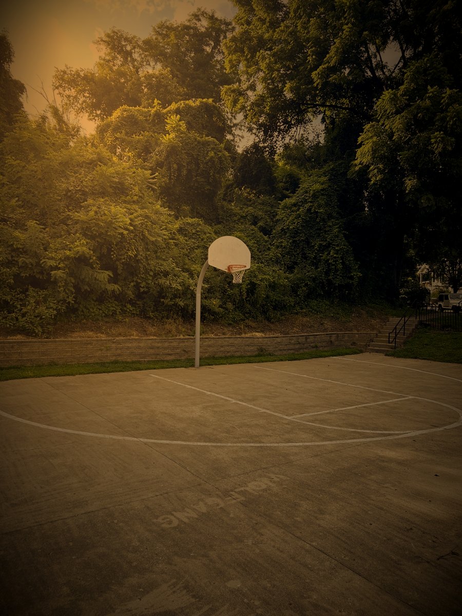Backboard and hoop above a concrete court backed by a stone retaining wall